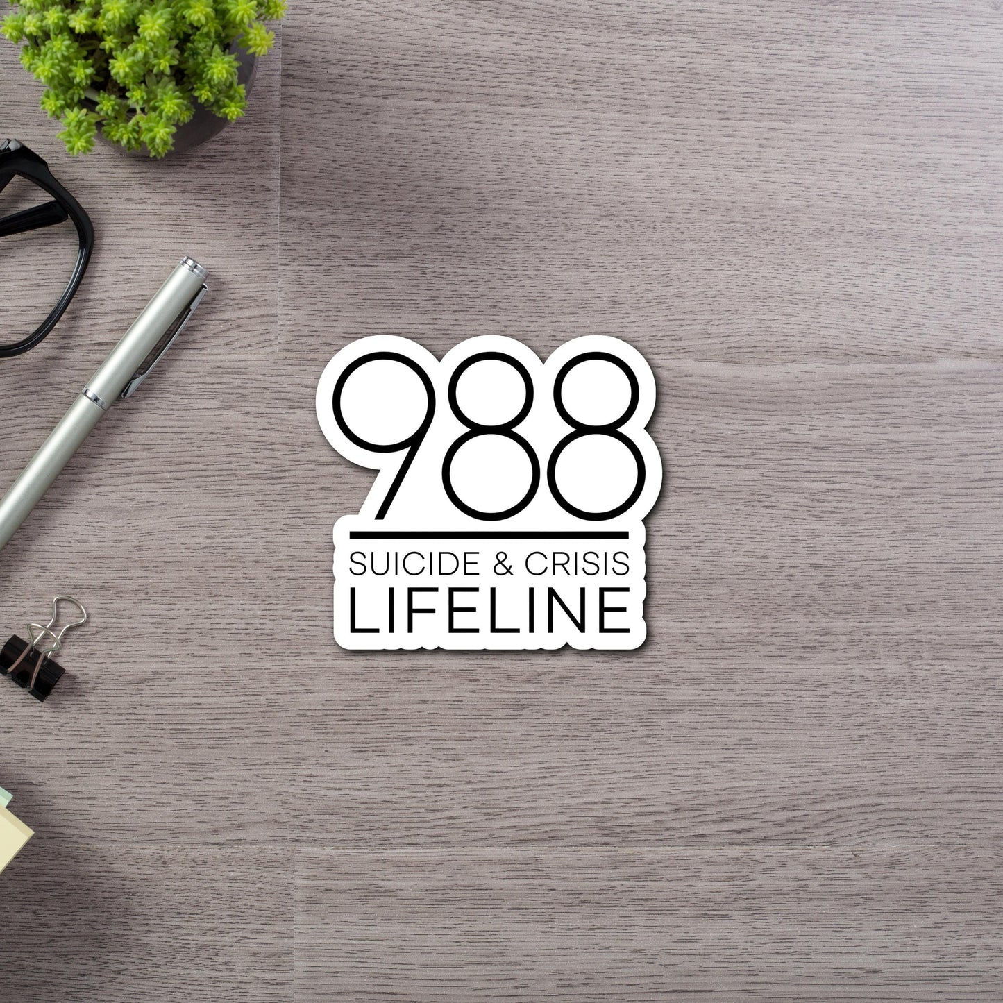988 Suicide & Crisis Lifeline Sticker - This is a die cut sticker with black font and large numbers 988 on top of lettering. Close Up view.