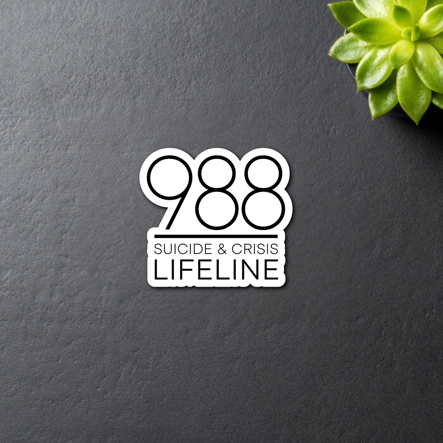 988 Suicide & Crisis Lifeline Sticker - in black bold font and white offset border around it. Close up on black background.