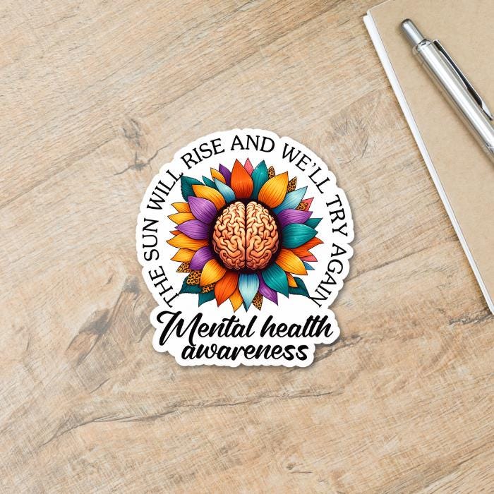 Mental Health Awareness Floral Brain Sticker - with white offset and black font on light wooden table.