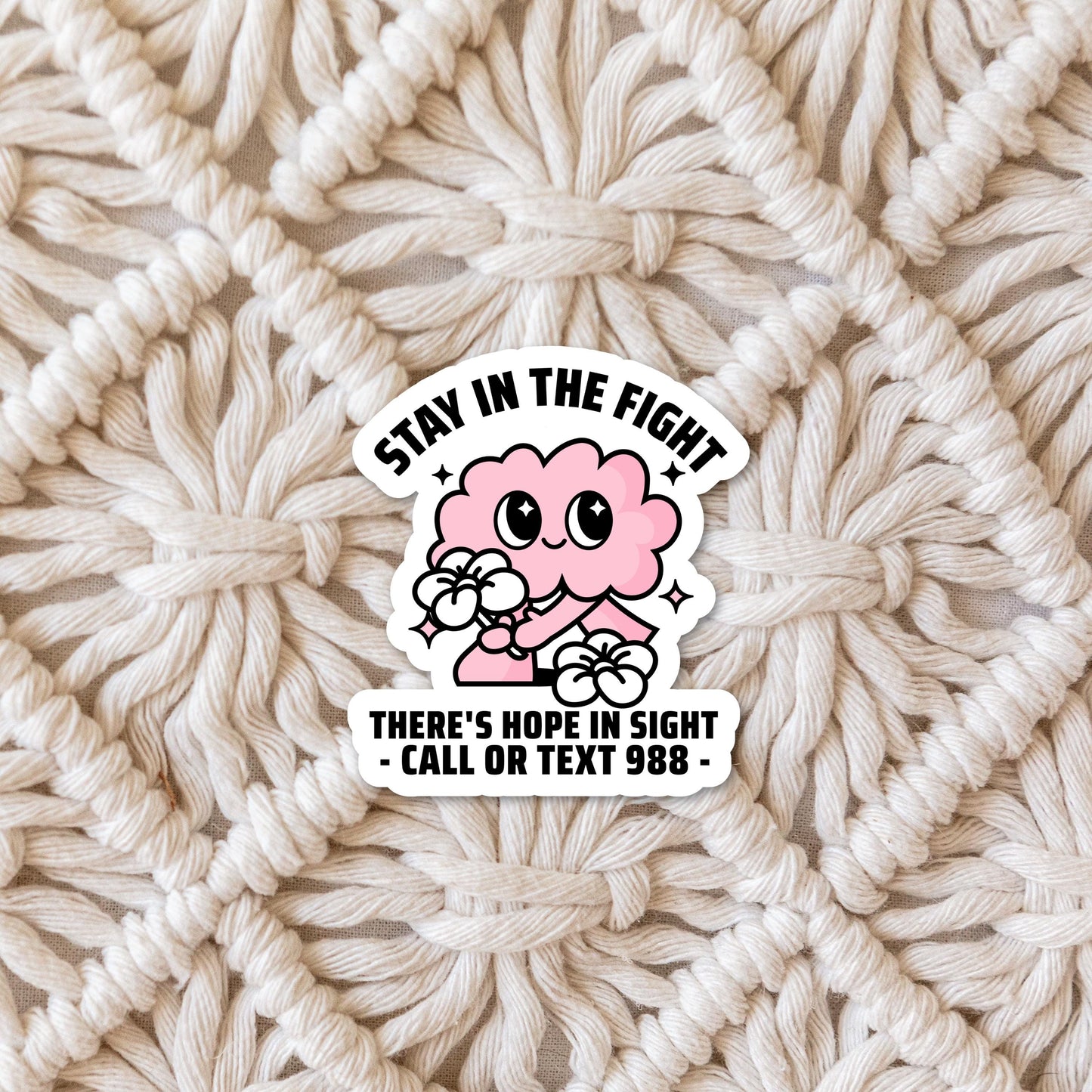 Suicide Prevention and Crisis Helpline Sticker - Cute Pink and White Brain Call or Text 988 Sticker with white offset border on woven mat background.