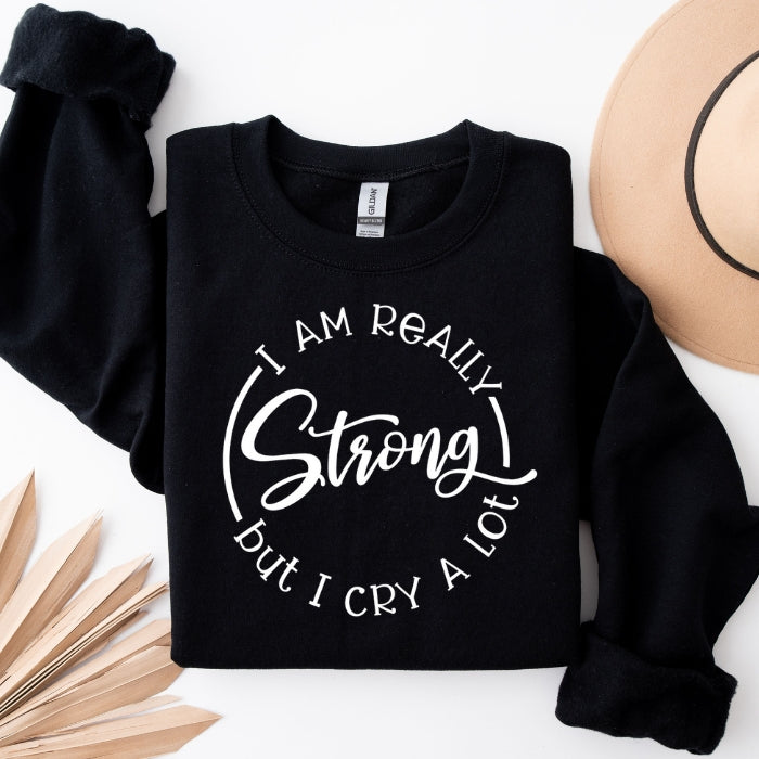 "Strong, but Cry A Lot" black crewneck sweatshirt, empowering and cozy. Perfect for women embracing their emotional strength, pairs well with leggings.