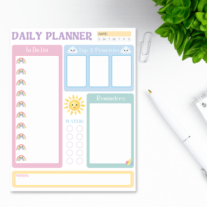 Pastel colored dated daily planner with cute kawaii elements sitting on a white desk top view.